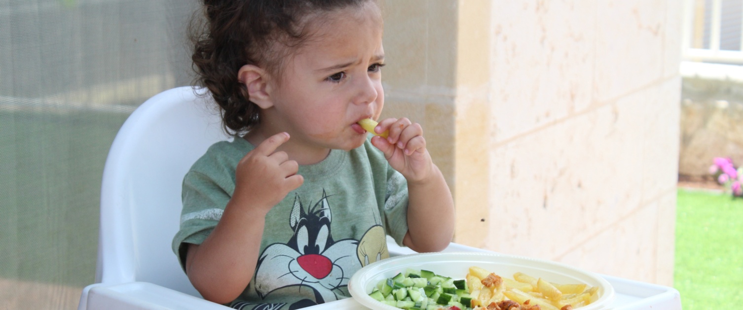 Image of a toddler in a highchair eating.