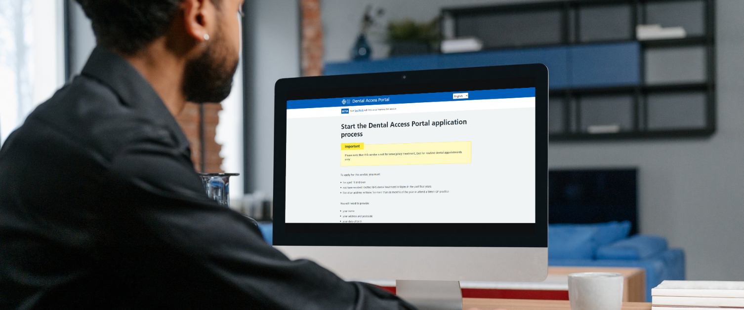 A person on a desktop computer with the main page of the Dental Access Portal open