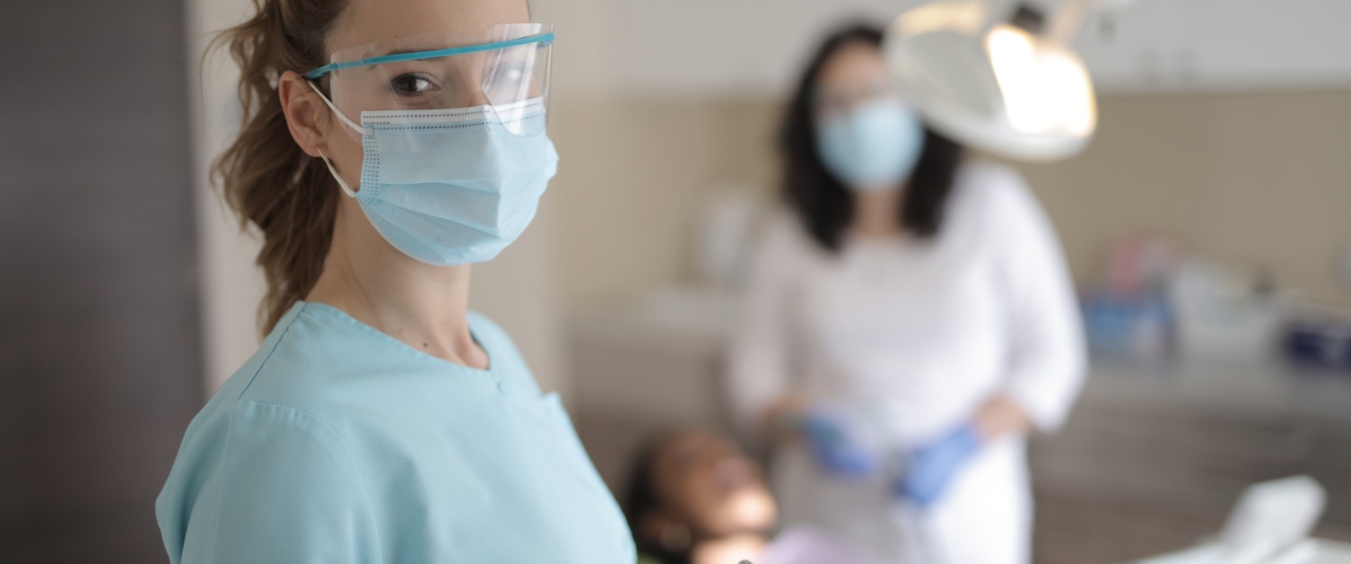 Young female dentist in medical uniform with instruments standing in clinic