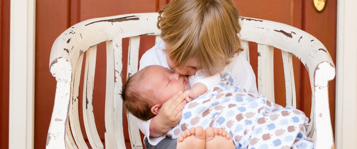 Boy kssing baby while sitting on a bench