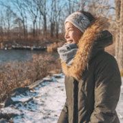 Image of woman in coat and scarf, outside in the snow.