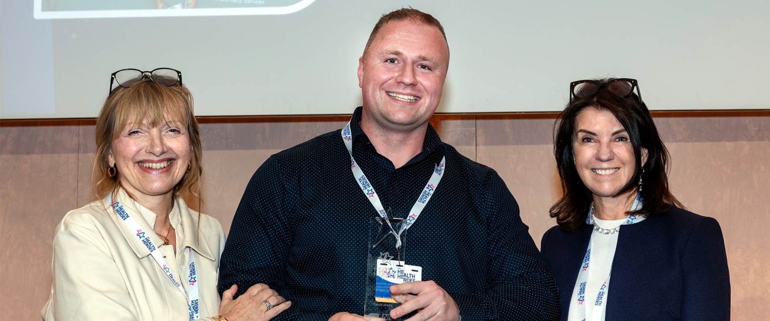 Claf ysbyty Caerdydd a drodd yn wirfoddolwr yn ennill gwobr genedlaethol fawreddog Llun o David gyda Catherine Johnstone CBE (Prif Weithredwr y Gymdeithas Wirfoddol Frenhinol) a Dr Dawn Harper (Darlledwr)