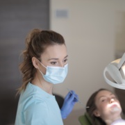 Canva - Serious young female dentist in medical mask working with patient in clinic.jpg