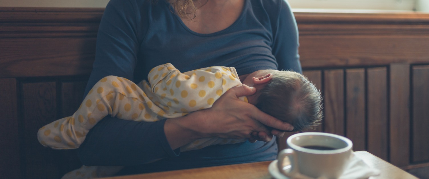 Woman breastfeeding baby in cafe