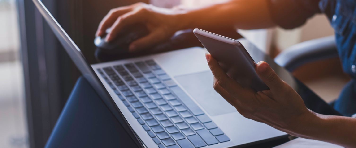 Person holding phone whilst using a laptop