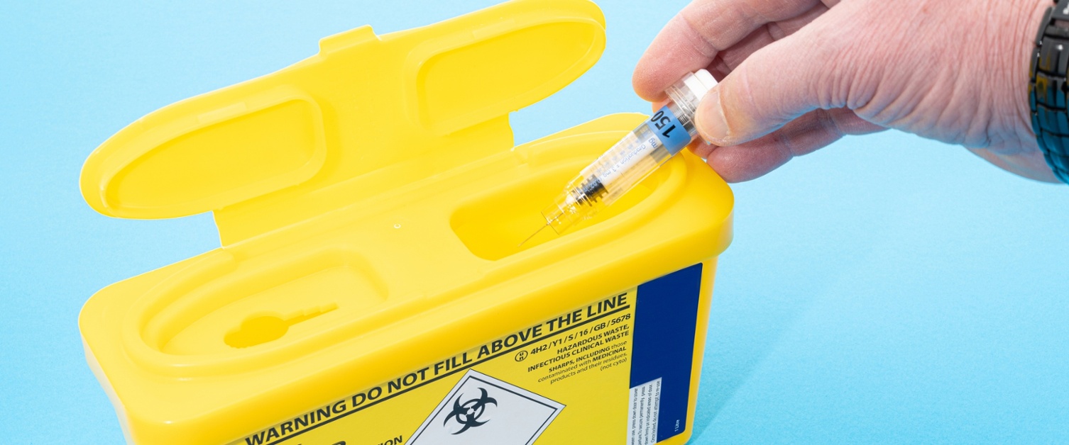 Person putting needles in a sharps box