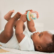 Baby lying on their back with both hands holding a toy