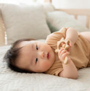 Baby lying on side holding a toy