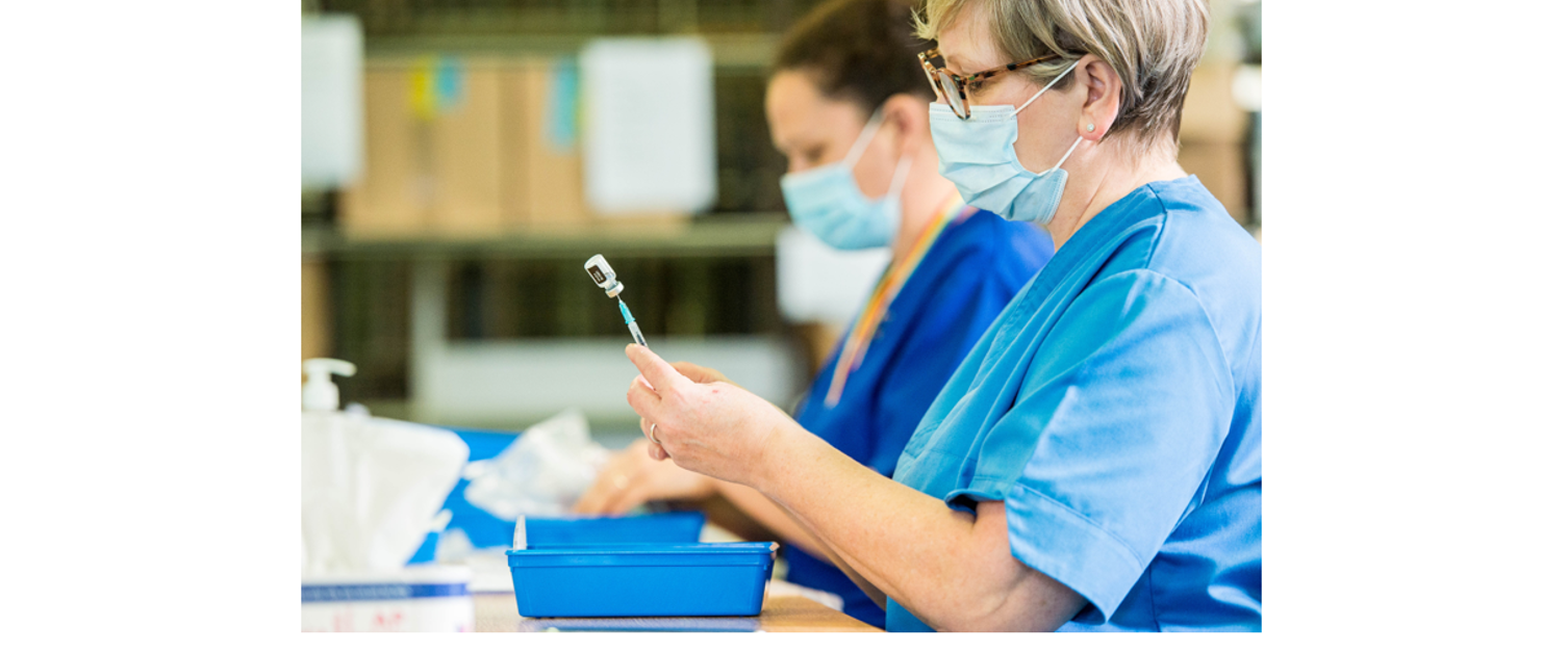 Nurse wearing a mask holding a vaccination