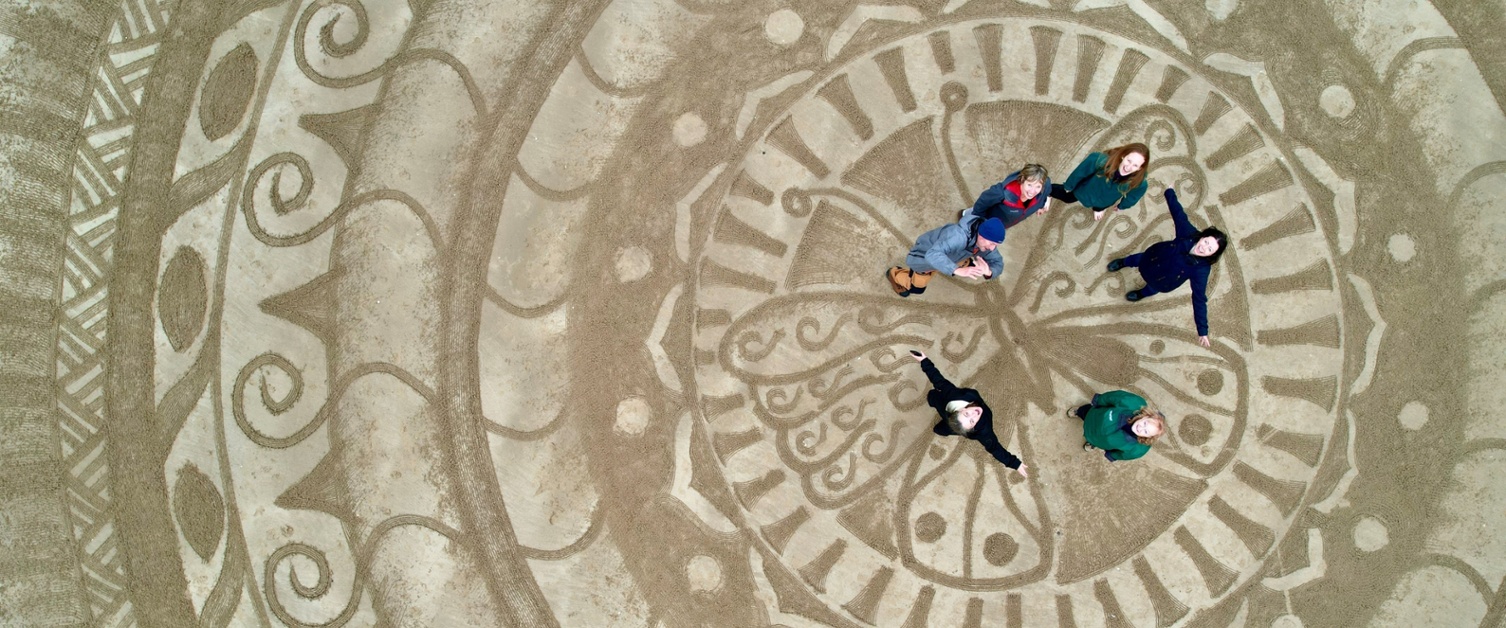 Group on people standing on sand art on a beach