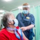 Nurse administers elderly patient vaccine