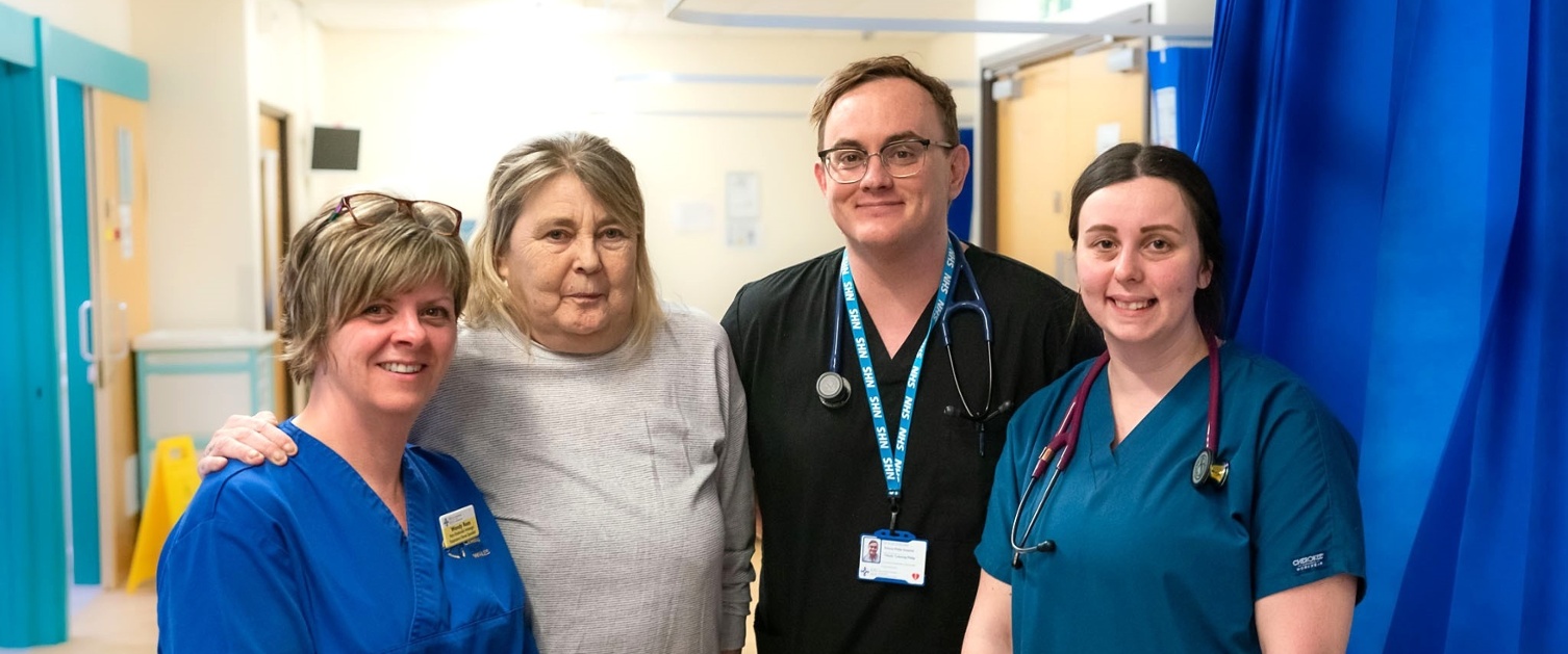 medical staff standing with patient, looking to camera