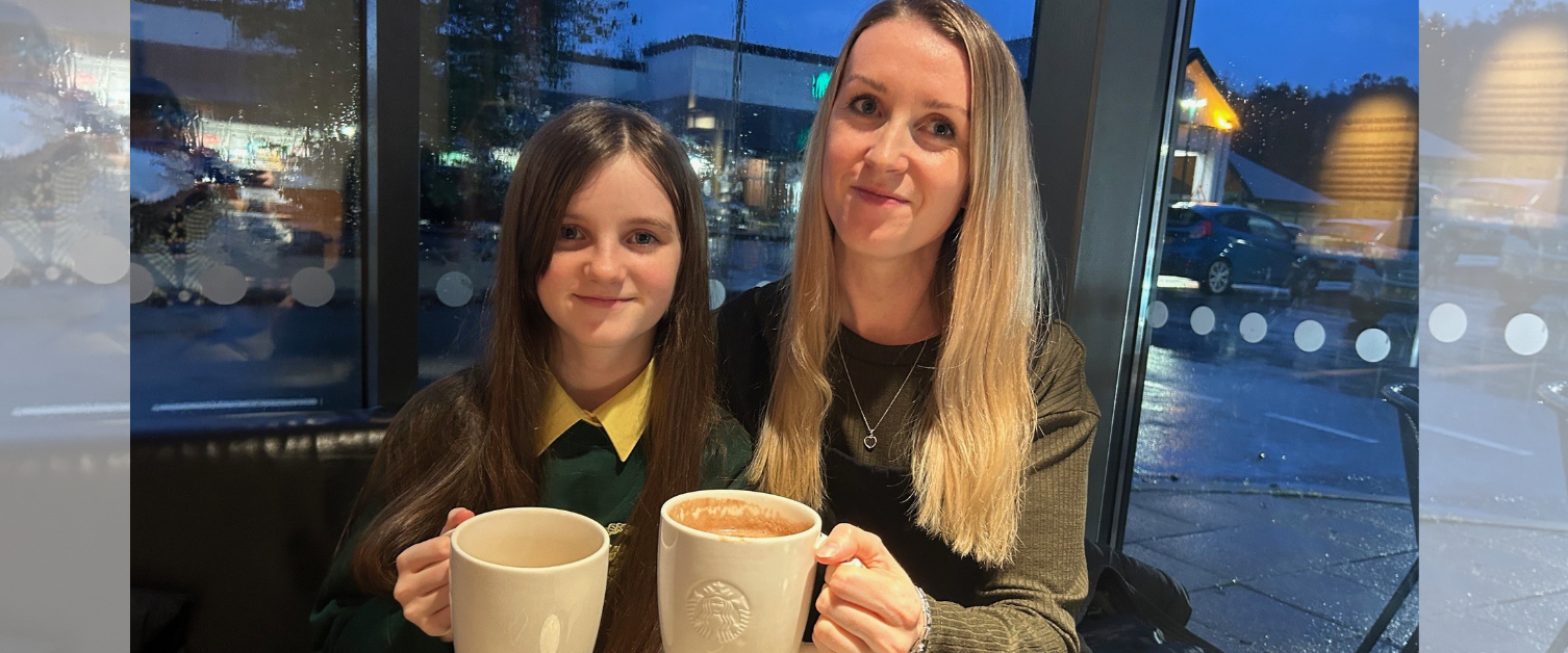 Mother, Katie and daughter, Seren hold cups of hot drinks in cafe