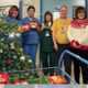 Group of nurses and volunteers standing next to Christmas tree with boxes of mince pies