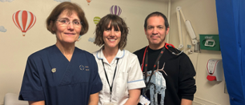 Three people in nursing uniforms standing together smiling at the camera