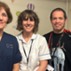 Three people in nursing uniforms standing together smiling at the camera