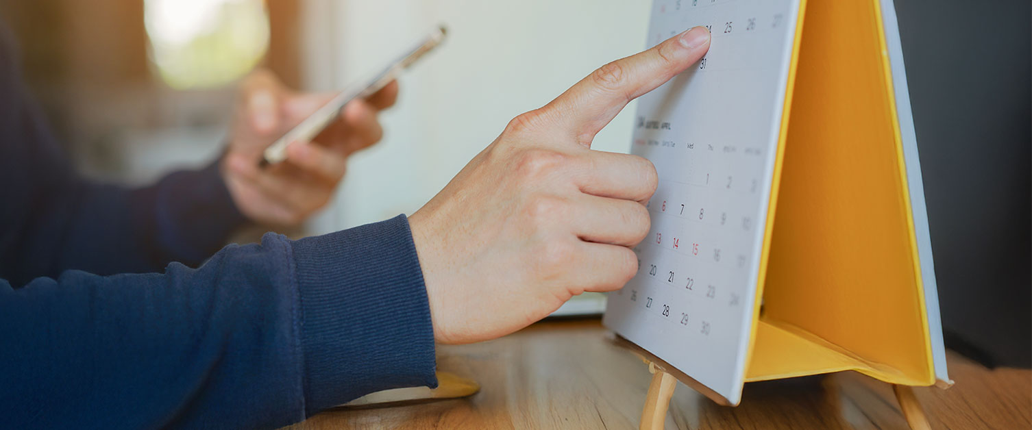 A person is pointing to a date on a calendar