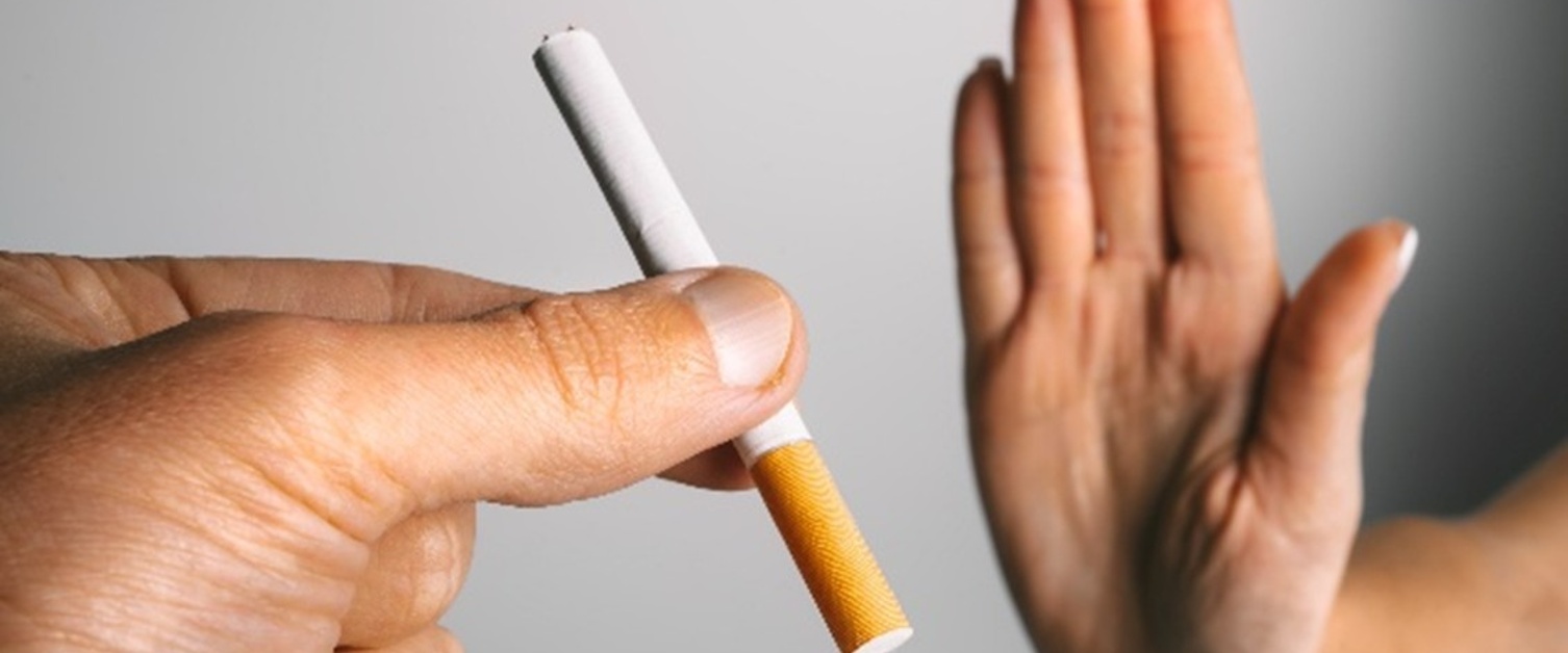 A hand offering an unlit cigarette and another hand held up to refuse it.