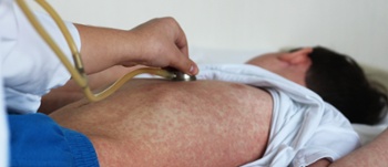 young boy with measles rash being checked by doctor