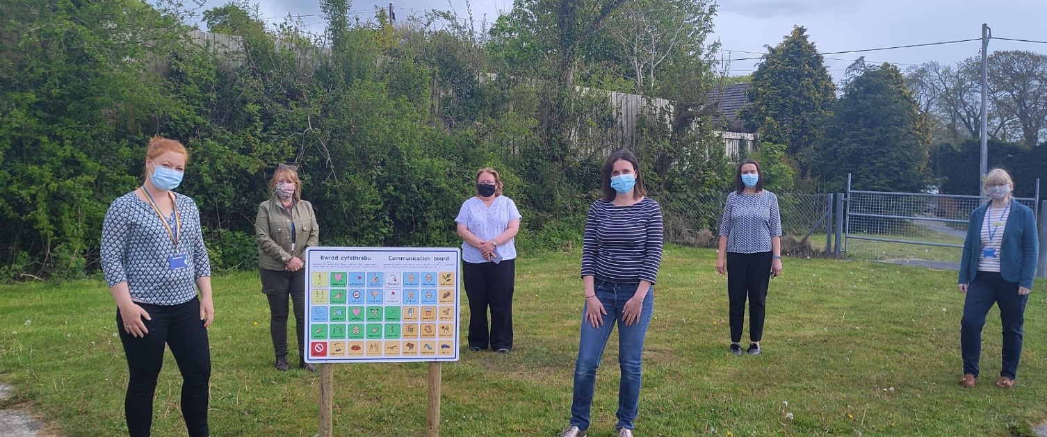 Group of adults standing around new communication board