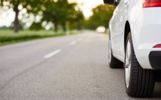 Image of the side of a silver car and the road surface.