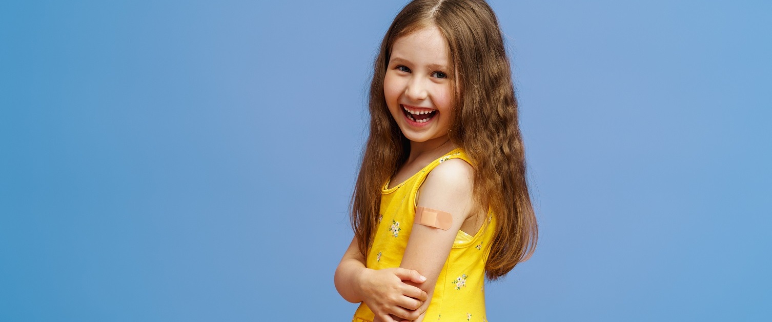 Smiling young child with sticking plaster on arm after a vaccination