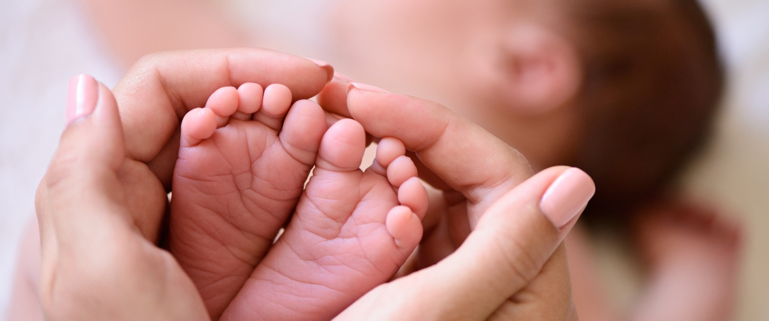 Hands holding feet of newborn