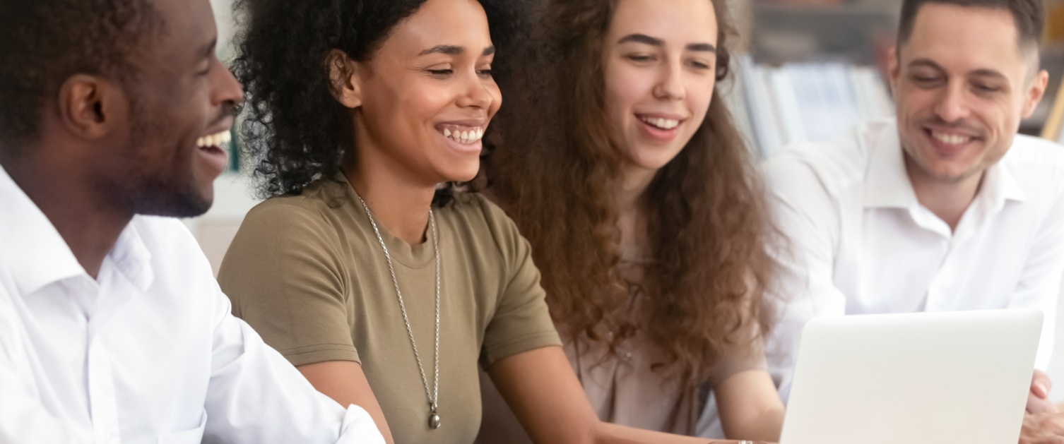 Group of young people sat around a laptop