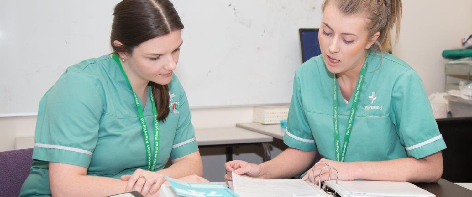 Two nurses consulting a book