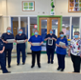 A group of nurses standing together in a semi-circle wearing masks and holding tablets to demonstrate how they use the Welsh Nursing Care Record