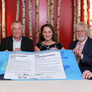 Representatives from Digital Health and Care Wales, Cwmpas and the Welsh Council for Voluntary Action hold a large, paper version of the Digital Inclusion Charter that