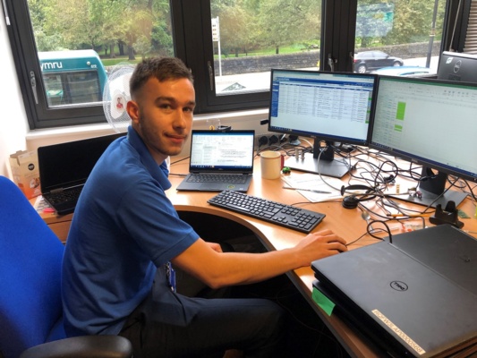 Man sitting at laptop with several screens working at Digital Health and Care Wales