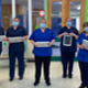 A group of nurses stand together in a hospital wearing masks and holding tablets that feature the Welsh Nursing Care Record