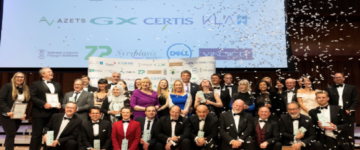 A group of people stood together on a stage, including a number of people holding awards.