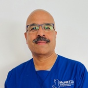 Dr Tanoj Kollamparambil in royal blue MoNET scrubs against a white background. 