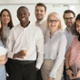 Group of office workers all standing together smiling at the camera. 