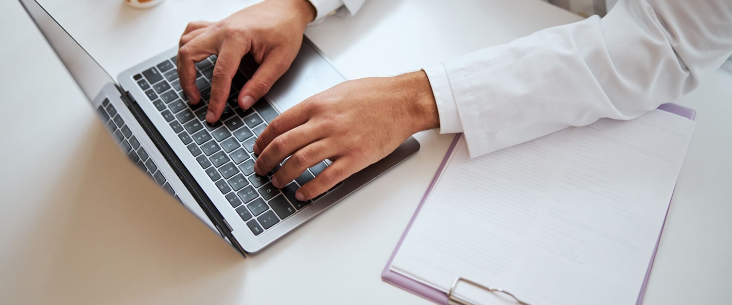 A doctor using a laptop on a desk