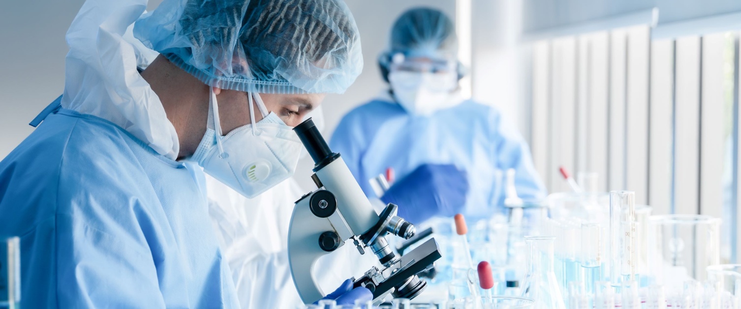 Healthcare worker using laboratory equipment and looking through a microscope. 