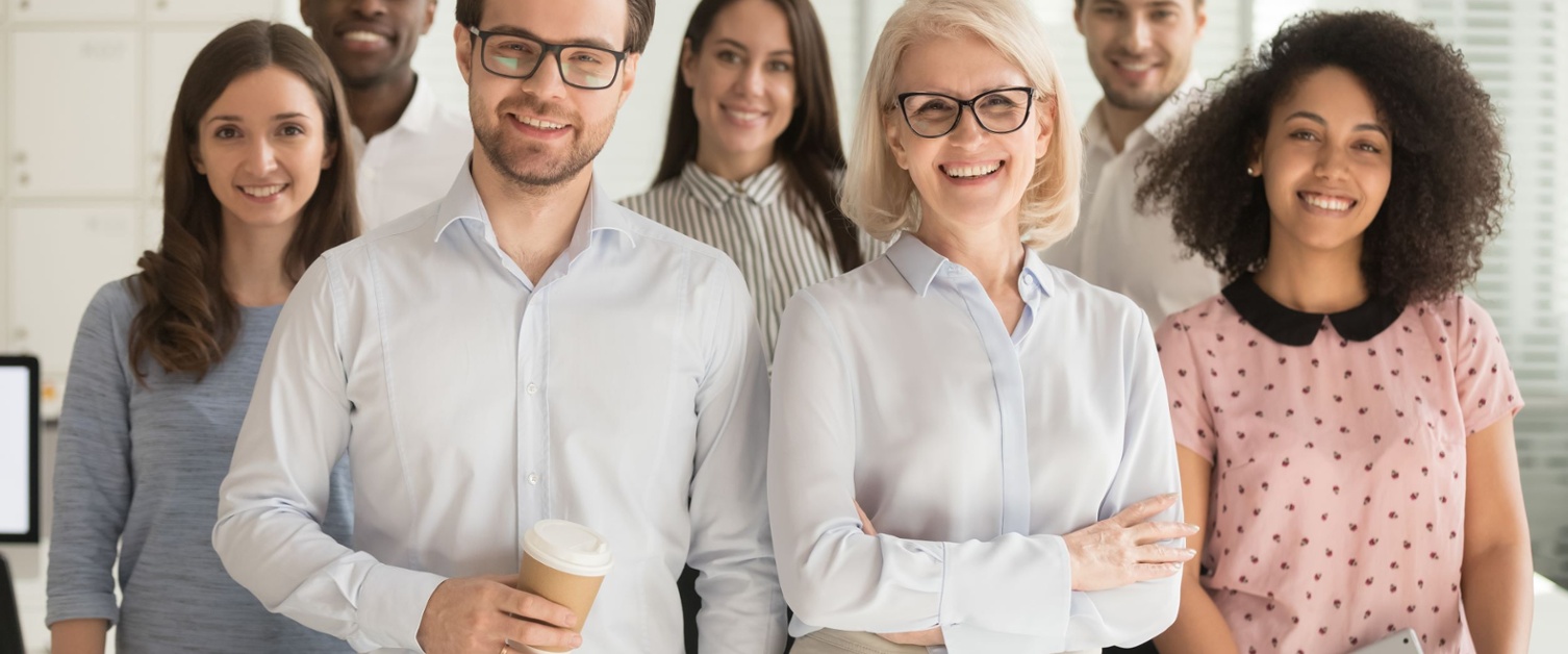 Employees of an organisation have a group photo in an office. 