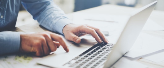 Individual typing on their laptop. 