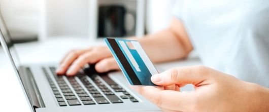 Person using their laptop while holding a credit card to indicate making a purchase. 