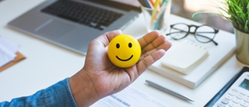 Image of Emoticon ball on male hand on work table.happy life concepts