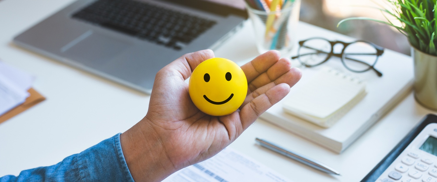 Image of Emoticon ball on male hand on work table.happy life concepts