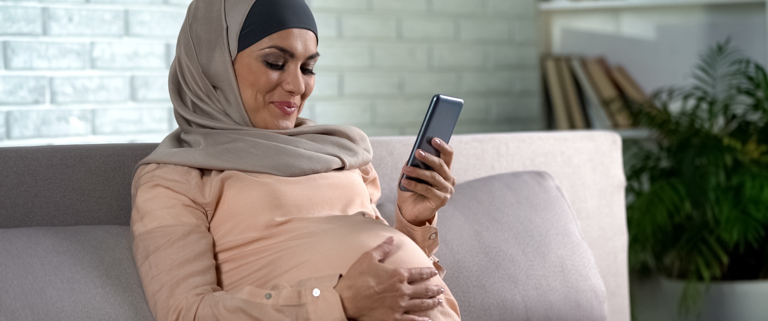 pregnant female watching video on smartphone home