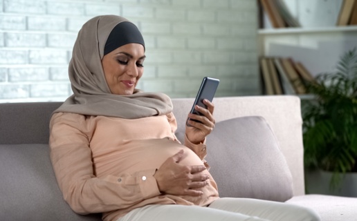 pregnant female watching video on smartphone home