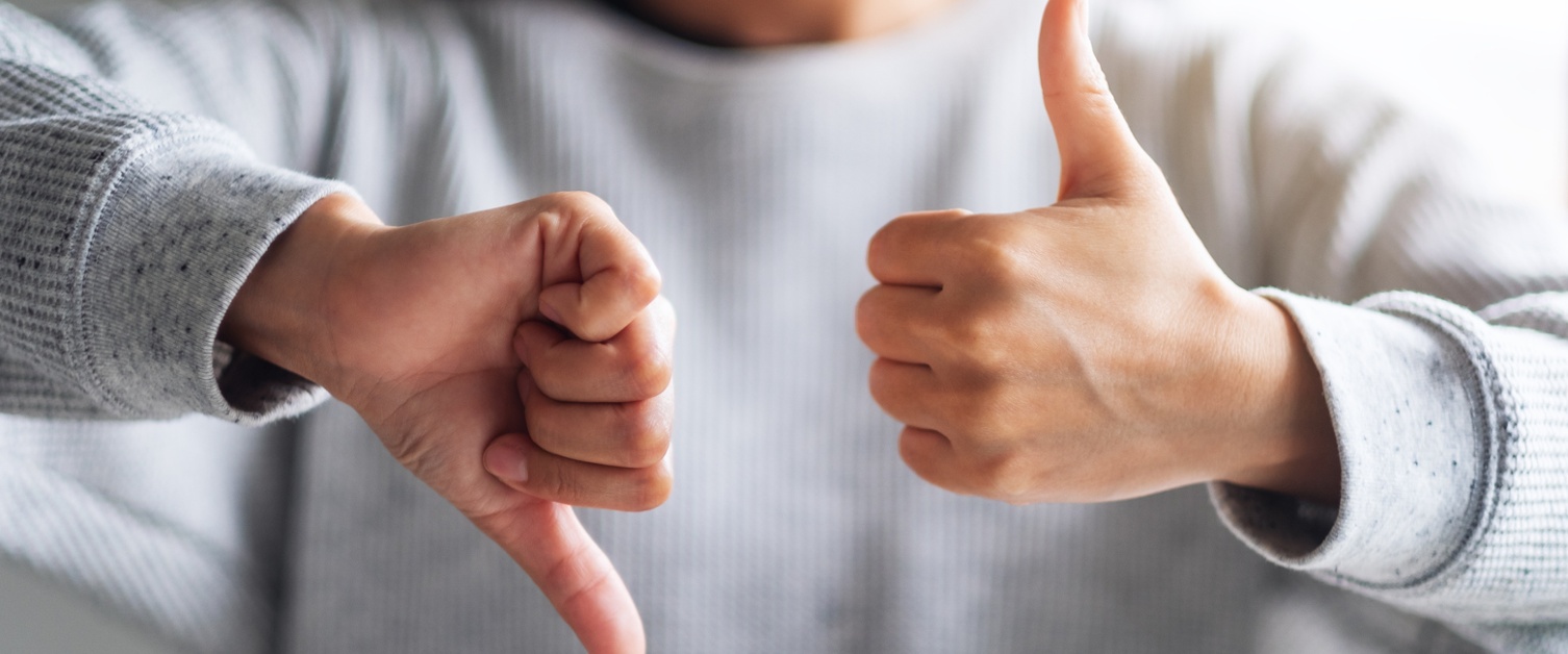Closeup image of a woman making thumbs up and thumbs down hands sign
