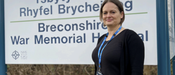 Lynda Mathias standing in front of Brecon War memorial hospital sign