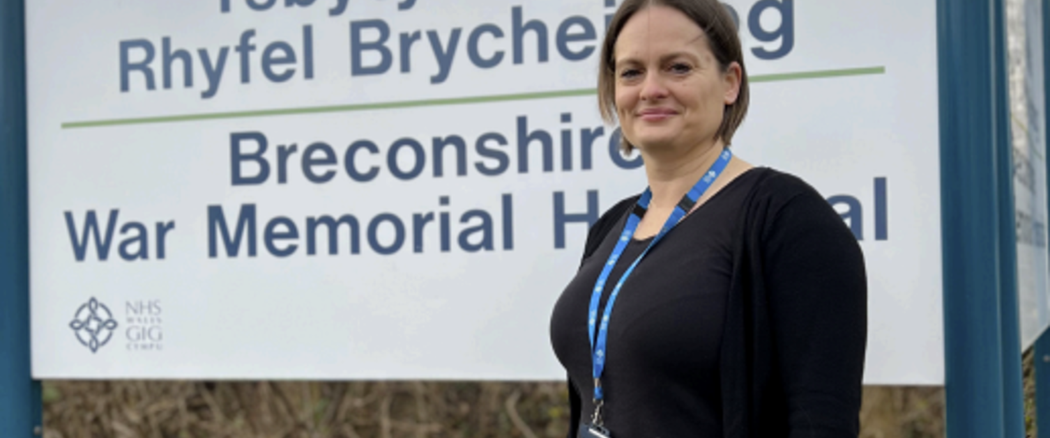 Lynda Mathias standing in front of Brecon War memorial hospital sign