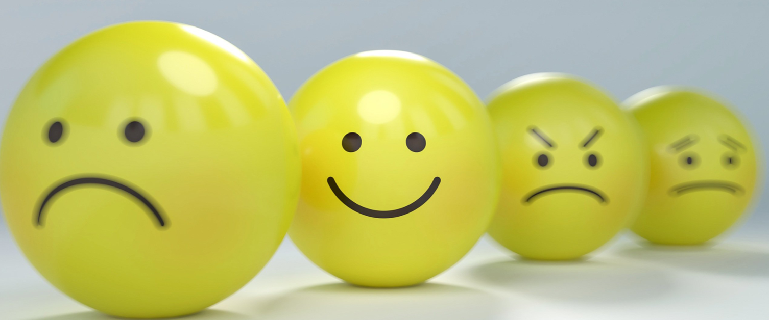 Image of 5 yellow balls with faces showing different emotions. Focus is on the smiley face.