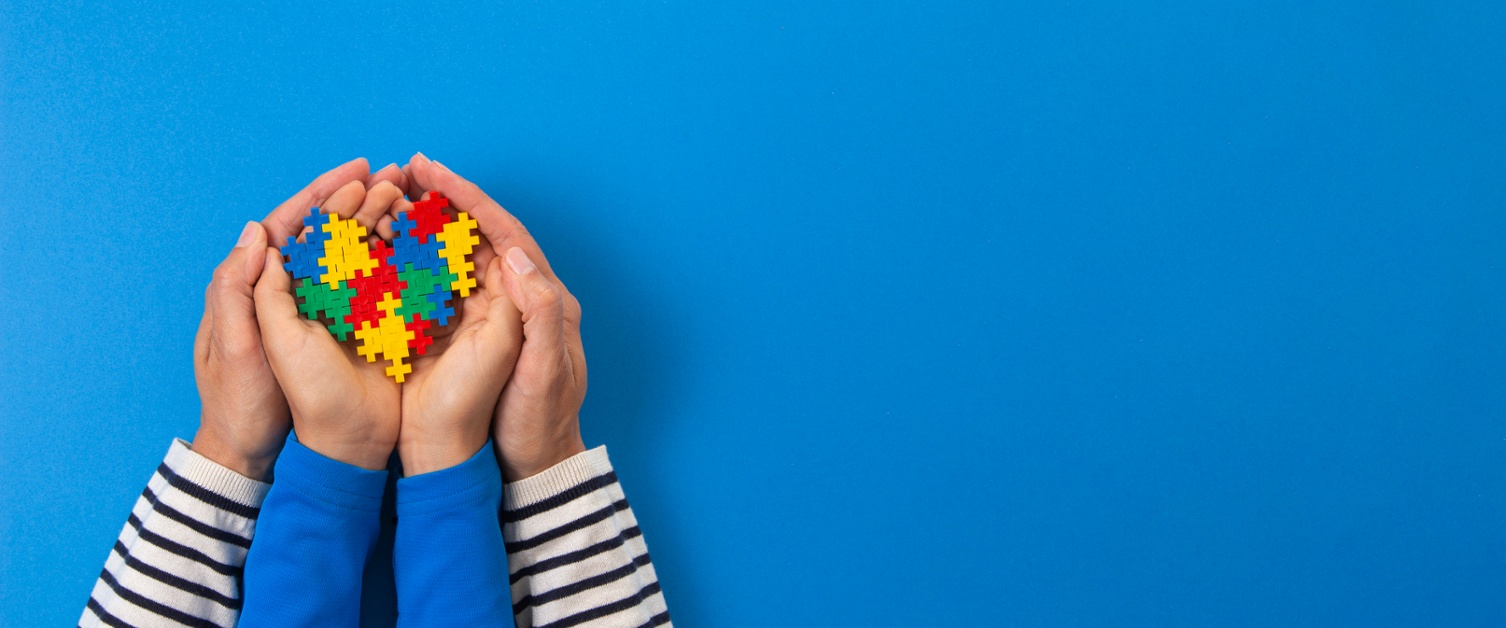 World autism awareness day concept. Adult and kid hands holding puzzle heart on light blue background